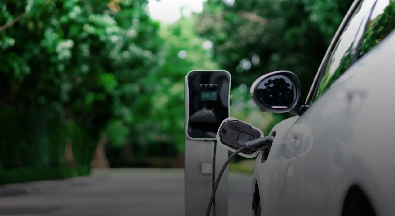 A white electric vehicle plugged into a charging station.