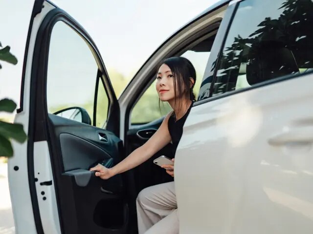 Young woman exiting the driver’s seat of a white minivan.